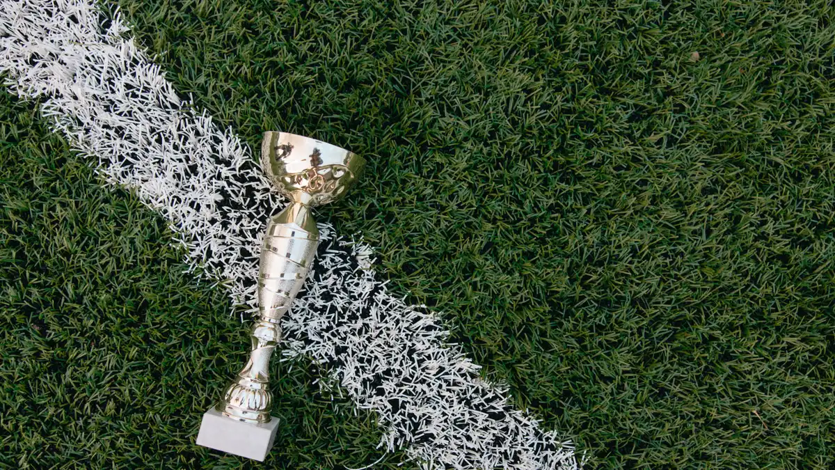 Small silver trophy lying across a white line on artificial turf